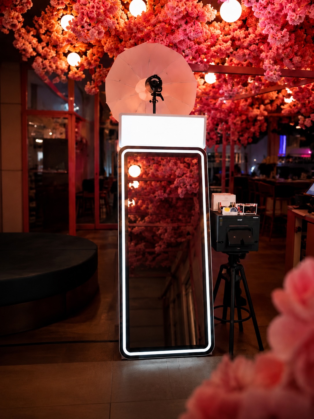 Miroir selfie LUMEA sous une pergola fleurie rose